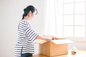 不要になった洋服を段ボールにしまっている女性