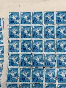 青色の背景に、鳥のモチーフが印象的な110円切手のシートです。